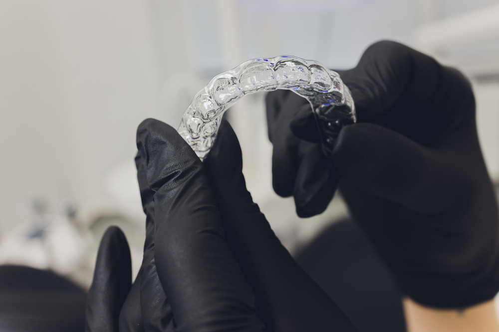 Clear aligner tray held in gloved hands for a clear braces treatment at ProsthDent in Magnolia, TX